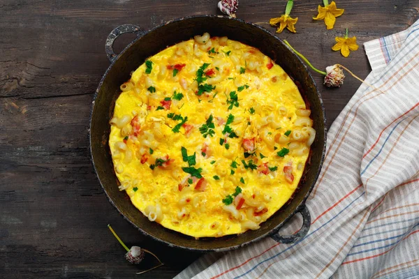 Pastırma, makarna ve Yeşiller eski siyah kızartma tavası vintage ahşap masa arka plan üzerinde tarih ile geleneksel rustik omlet. Kopya alanı