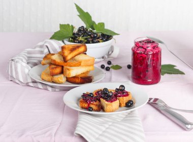 Ev yapımı frenk üzümü reçeli çatal ve bıçak üzerinde parlak koyu kırmızı masa örtüsü ile lezzetli tost ekmeği