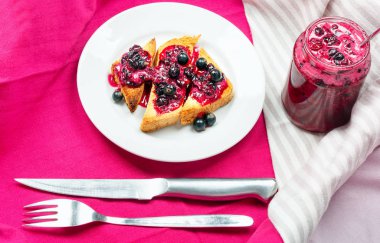 Ev yapımı frenk üzümü reçeli çatal ve bıçak üzerinde parlak koyu kırmızı masa örtüsü ile lezzetli tost ekmeği