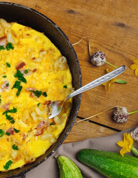 Pastırma, makarna ve Yeşiller eski siyah kızartma tavası vintage ahşap masa arka plan üzerinde tarih ile geleneksel rustik omlet. Kopya alanı