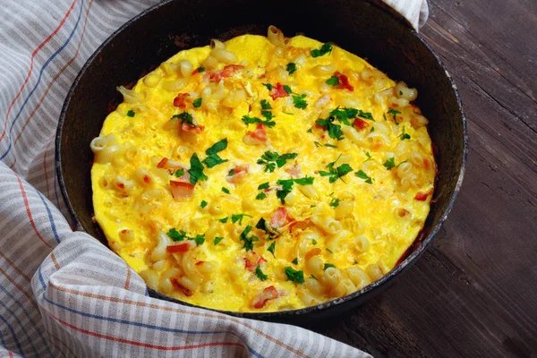 Pastırma, makarna ve Yeşiller eski siyah kızartma tavası vintage ahşap masa arka plan üzerinde tarih ile geleneksel rustik omlet. Kopya alanı