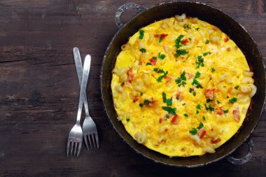 Pastırma, makarna ve yeşillik üzerinde eski siyah kızartma tavası ile geleneksel rustik omlet