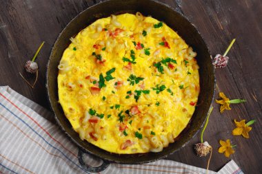 Pastırma, makarna ve Yeşiller eski siyah kızartma tavası vintage ahşap masa arka plan üzerinde tarih ile geleneksel rustik omlet. Kopya alanı