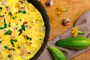 Pastırma, makarna ve Yeşiller eski siyah kızartma tavası vintage ahşap masa arka plan üzerinde tarih ile geleneksel rustik omlet. Kopya alanı