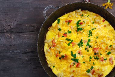 Pastırma, makarna ve Yeşiller eski siyah kızartma tavası vintage ahşap masa arka plan üzerinde tarih ile geleneksel rustik omlet. Kopya alanı