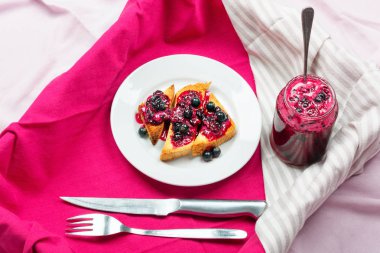 Ev yapımı frenk üzümü reçeli çatal ve bıçak üzerinde parlak koyu kırmızı masa örtüsü ile lezzetli tost ekmeği