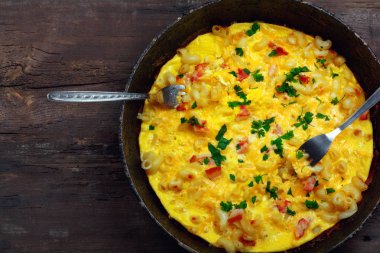 Pastırma, makarna ve yeşillik üzerinde eski siyah kızartma tavası ile geleneksel rustik omlet