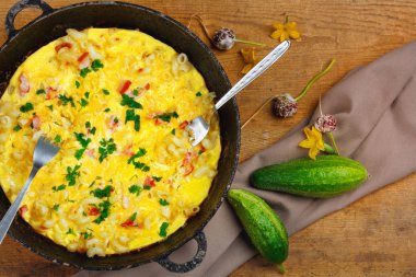 Pastırma, makarna ve Yeşiller eski siyah kızartma tavası vintage ahşap masa arka plan üzerinde tarih ile geleneksel rustik omlet. Kopya alanı