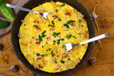 Pastırma, makarna ve Yeşiller eski siyah kızartma tavası vintage ahşap masa arka plan üzerinde tarih ile geleneksel rustik omlet. Kopya alanı