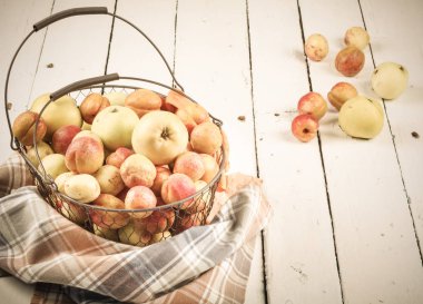 Olgun taze kayısılar ve elmalar dokunmuş metal sepetin içinde odasındaki ahşap masanın üzerinde.