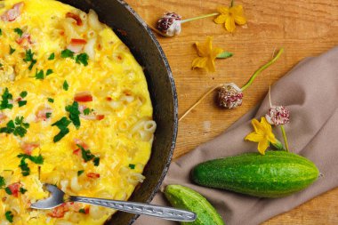 Pastırma, makarna ve Yeşiller eski siyah kızartma tavası vintage ahşap masa arka plan üzerinde tarih ile geleneksel rustik omlet. Kopya alanı