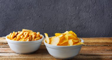 Tuzlu atıştırmalıklar. Cips, kraker kase tuğla duvar ahşap tablo