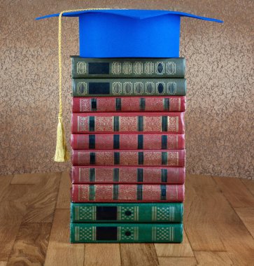 Mezuniyet kolej duvar arka plan üzerinde ahşap masa üzerinde kitap yığını üzerine