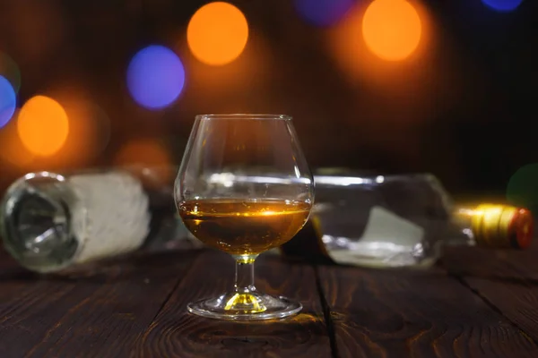 Szklankę Whisky Lub Brandy Pustych Butelek Drewnianym Stole Jasnym Tle — Zdjęcie stockowe