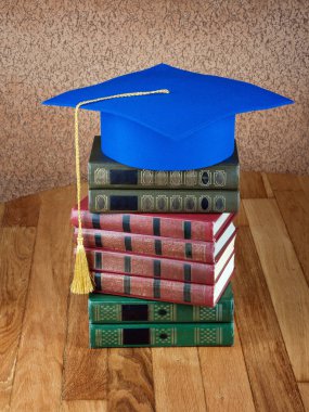 Mezuniyet kolej duvar arka plan üzerinde ahşap masa üzerinde kitap yığını üzerine