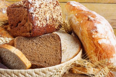 Ahşap masa üzerinde hasır sepet içinde kaba taşlama, çavdar ve buğday unu ekmek