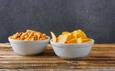 Tuzlu atıştırmalıklar. Cips, kraker kase tuğla duvar ahşap tablo