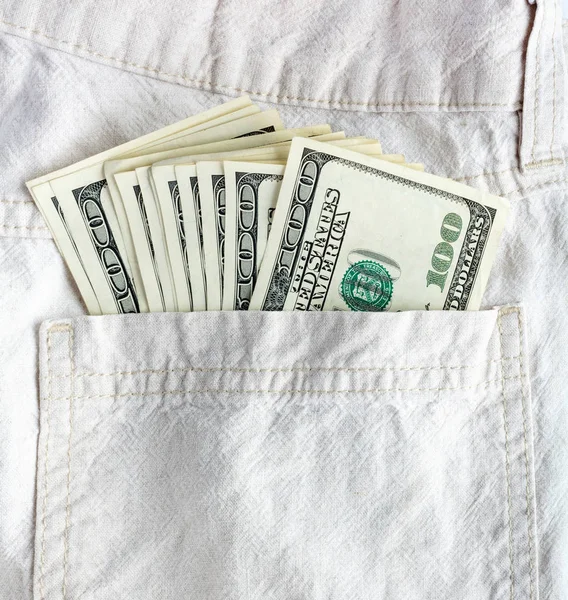 Hundred dollar bills sticking in the back pocket of denim blue jeans