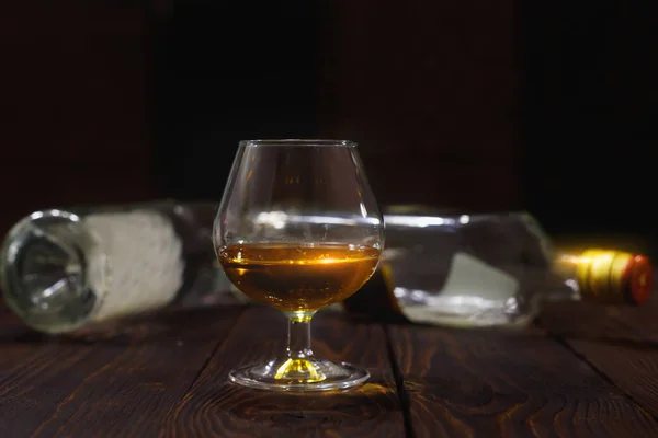 Bicchiere Whisky Brandy Bottiglie Vuote Tavolo Legno Sfondo Nero — Foto Stock