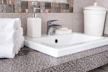 Modern banyodaki seramik tezgahta bir yığın temiz beyaz havlu.