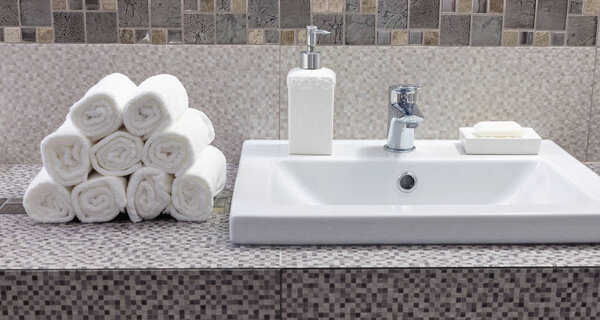 Stack of clean white towels on ceramic countertop in modern bathroom