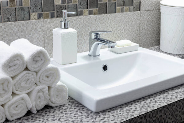 Stack of clean white towels on ceramic countertop in modern bathroom