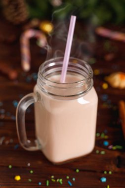 Cam fincan sıcak kakao rustik ahşap masa üzerinde süt, tarçın ve saman tuplü