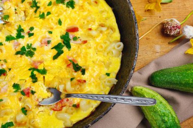 Pastırma, makarna ve Yeşiller eski siyah kızartma tavası vintage ahşap masa arka plan üzerinde tarih ile geleneksel rustik omlet. Kopya alanı