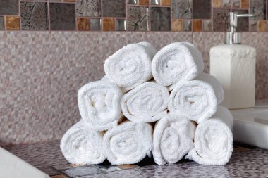 Modern banyodaki seramik tezgahta bir yığın temiz beyaz havlu.