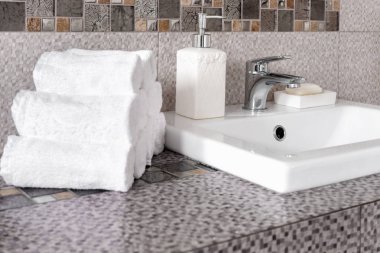 Modern banyodaki seramik tezgahta bir yığın temiz beyaz havlu.