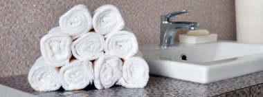 Modern banyodaki seramik tezgahta bir yığın temiz beyaz havlu.