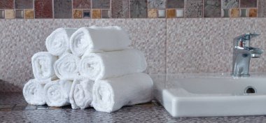 Modern banyodaki seramik tezgahta bir yığın temiz beyaz havlu.