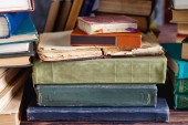 Stoh starých historických knih na dřevěné polici v univerzitní knihovně pro čtení
