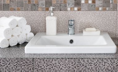 Modern banyodaki seramik tezgahta bir yığın temiz beyaz havlu.