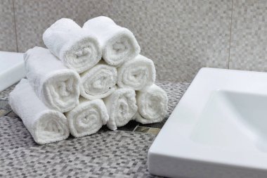 Modern banyodaki seramik tezgahta bir yığın temiz beyaz havlu.