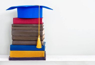 Mezuniyet mavi kolej duvar arka plan üzerinde ahşap raf kitap yığını üzerine