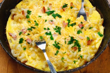 Pastırma, makarna ve yeşillik üzerinde eski siyah kızartma tavası ile geleneksel rustik omlet