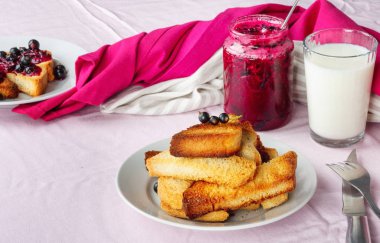 Lezzetli tost ekmeği ev yapımı frenk üzümü reçeli ve parlak kırmızı masa örtüsü üzerinde süt.
