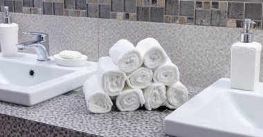 Modern banyodaki seramik tezgahta bir yığın temiz beyaz havlu.