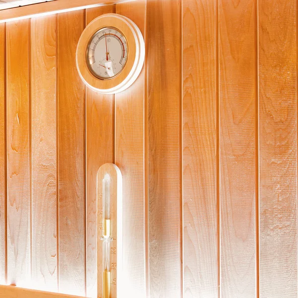 Round thermometer and hourglass on the wall of traditional sauna — Stock Photo, Image