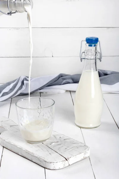 Старые бутылки винтажного стиля со свежим молоком на белом деревянном столе — стоковое фото
