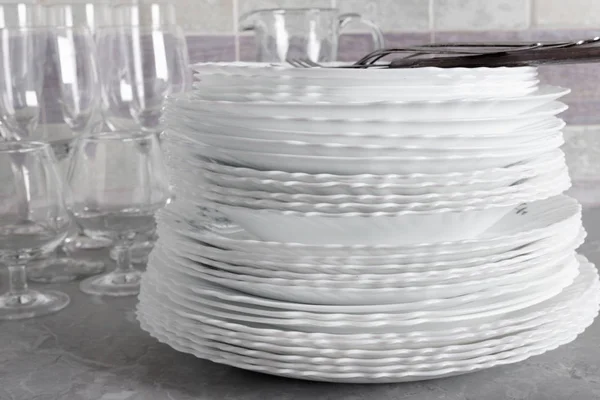 Stapel sauberer Teller mit Gabeln, Messern und Gläsern zum Servieren — Stockfoto