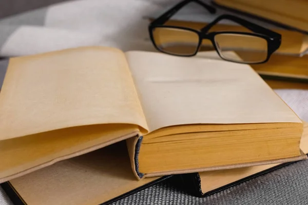 Стопка открытых винтажных книг с очками — стоковое фото