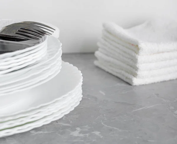 Stack of clean plates with forks, knives and glasses for serving — Stock Photo, Image