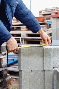 İşçi depodaki beton yapı taşlarını ölçüyor 