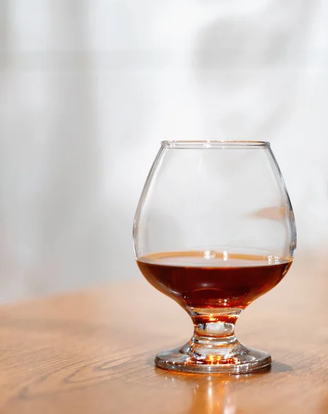 One glass of brandy on antique wooden counter top — Stock Photo, Image