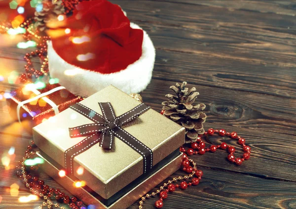 밝은 빛나는 배경에 구슬, 장난감 및 산타 클로스 모자가있는 선물 상자 — 스톡 사진
