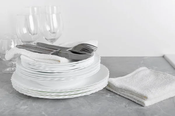 Pilha de pratos limpos com garfos, facas e copos para servir — Fotografia de Stock
