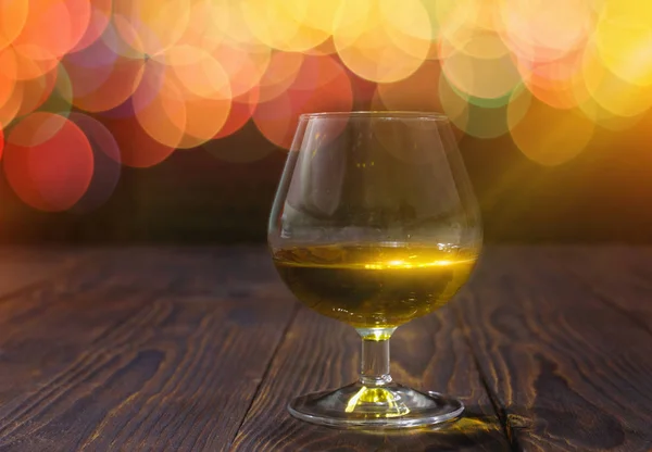 Glas Whisky oder Brandy auf Holztisch auf hell glühendem Hintergrund — Stockfoto