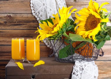 Eski ahşap duvarda ayçiçeği dalları ile taze kabak ve portakal suyu 